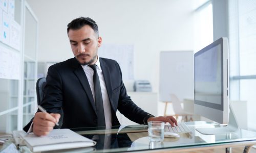 caucasien-homme-affaires-s-asseoir-bureau-devant-ordinateur-ecrire-dossier